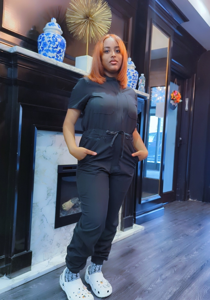 Upgrade your workwear with the Black Scrubs Romper for Women. Breathable stretch fabric, ribbed bottom fit, and deep pockets. A sleek, modern medical scrub jumpsuit.